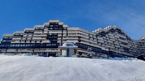 A modern building with a unique architectural design, featuring multiple balconies and a central structure.