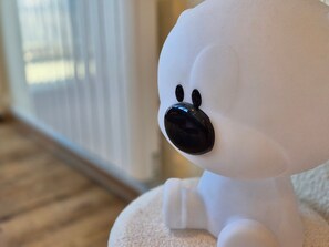 A plush toy with a black nose and two black eyes, sitting on a white surface.