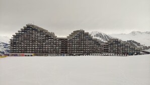 A multi-story hotel with a modern architectural design, featuring balconies and a flat roof.
