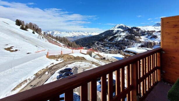 A snow-covered mountain landscape with a wooden balcony railing.