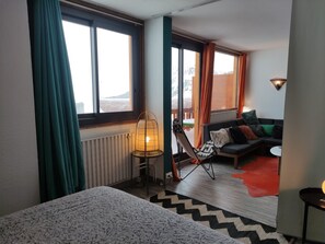 Una habitación con cama, sofá, sillón y vistas al exterior.