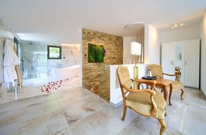 Enjoy a refreshing soak in the large bathtub or invigorate with a shower, surrounded by a stylish bathroom with a vanity and chair.