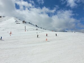 A snowy ski slope with skiers and a clear sky.