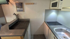 A compact kitchen with a microwave, a sink, and a small countertop. - Cozy studio with direct slope access, slope view, pets allowed (Plagne Aime 2000)