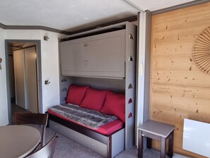 A compact room with a bed, a small table, and a chair.