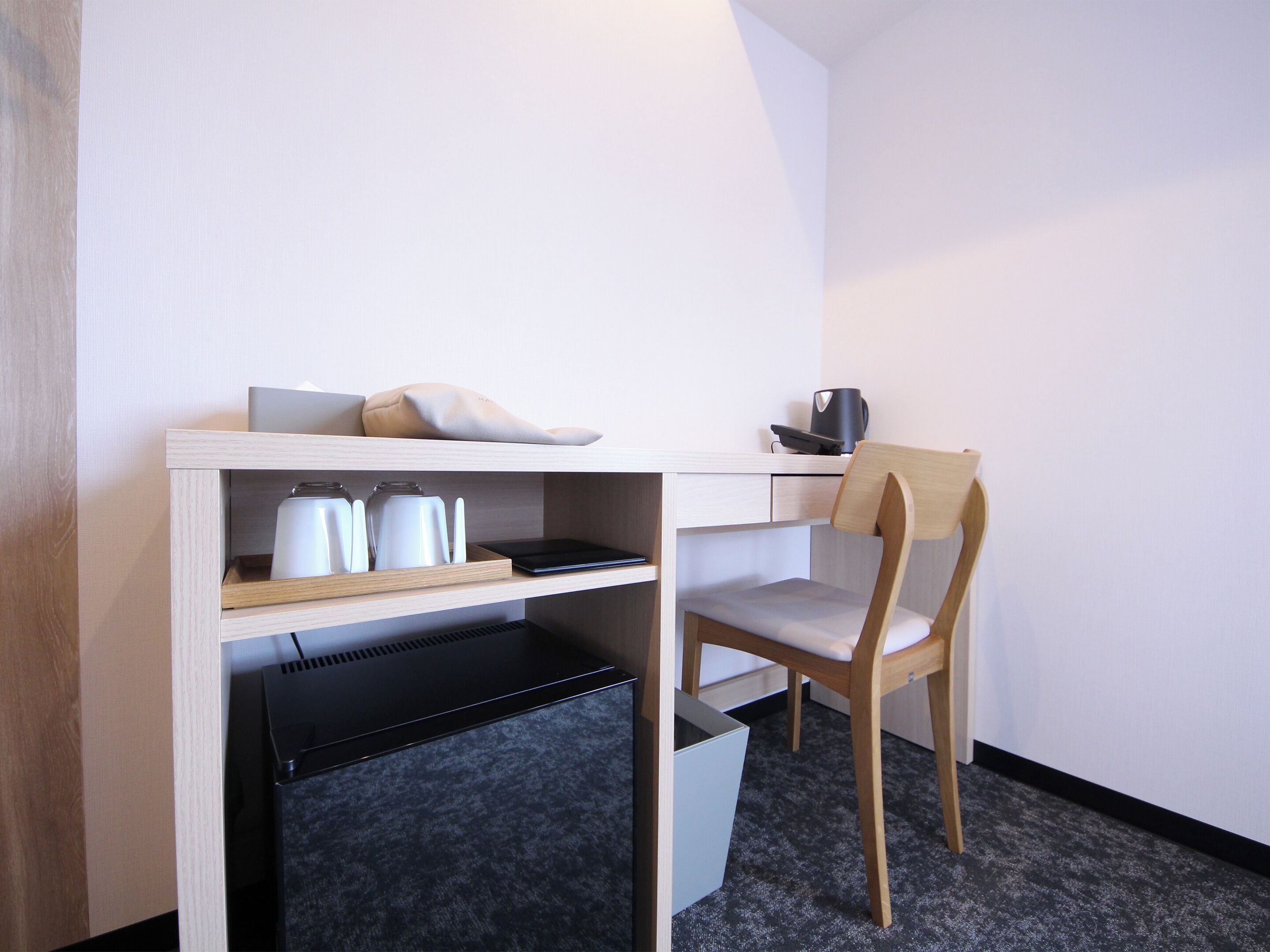A small, modern workspace with a desk, chair, and storage compartments.