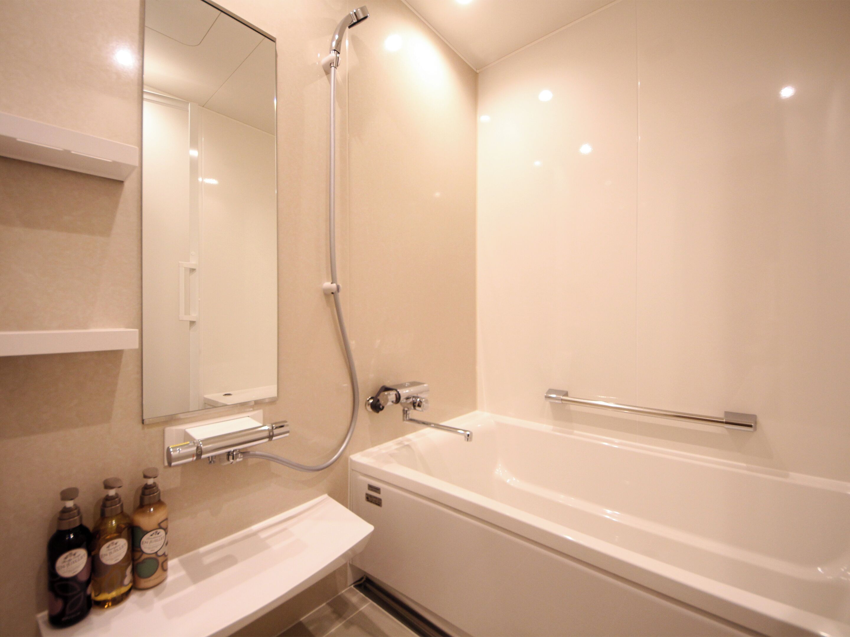 Een moderne badkamer met een bad, douche en een wastafel met toiletartikelen.