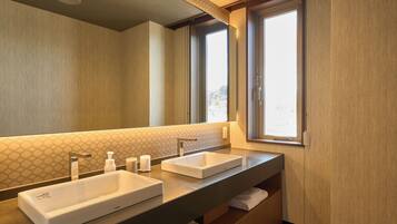 A modern bathroom with two sinks, a large mirror, and a window providing natural light.