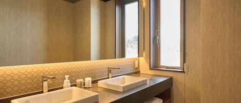 A modern bathroom with two sinks, a large mirror, and a window providing natural light.