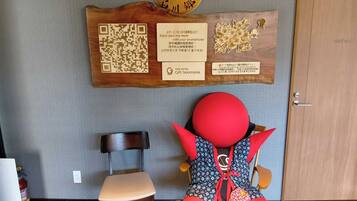 A wooden wall with a QR code, a wooden plaque with text, and a plush toy on a chair.
