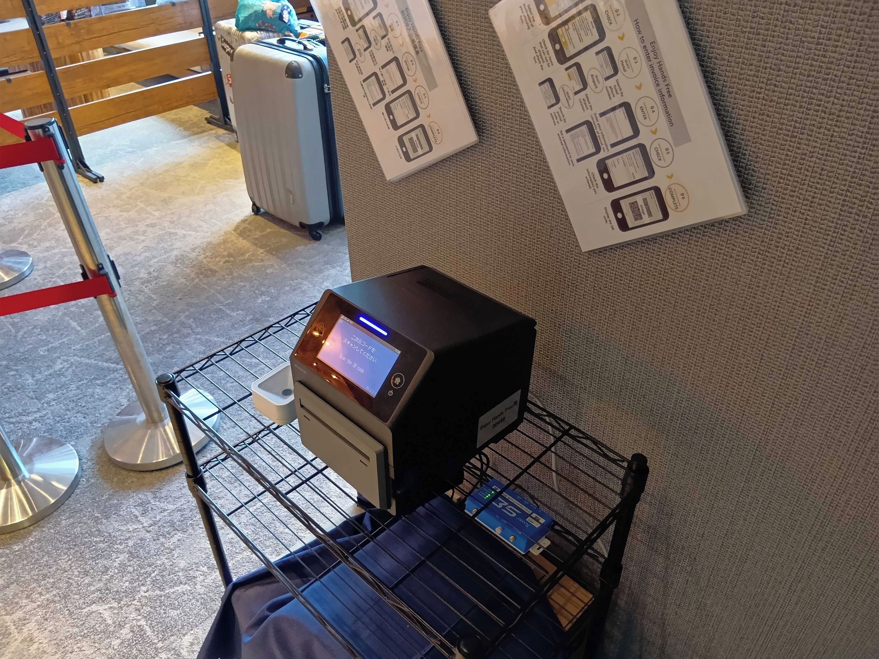 A self-service kiosk with a digital display, a luggage cart, and a wall-mounted information board.