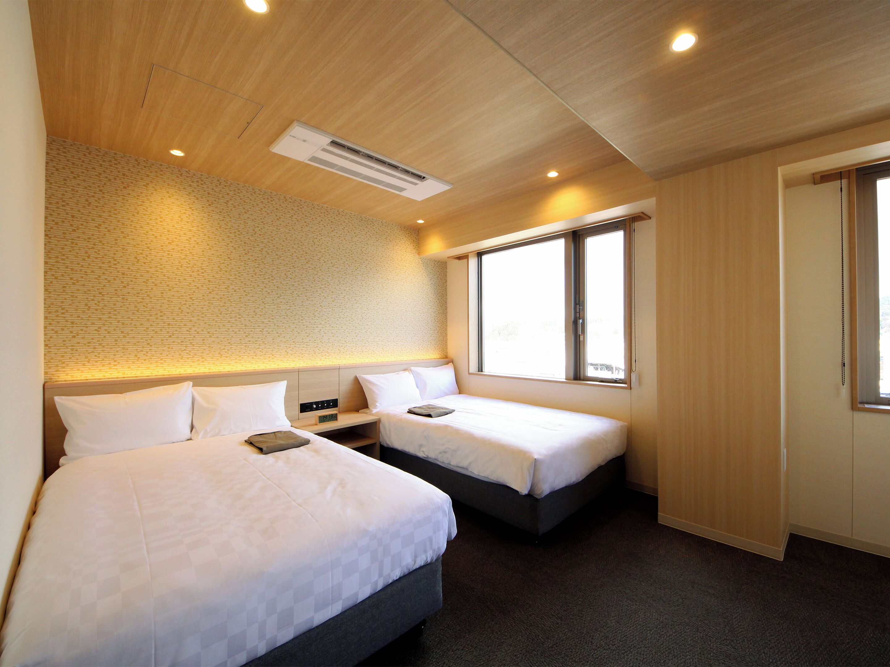 Een hotelkamer met twee bedden, een groot raam en een houten plafond.