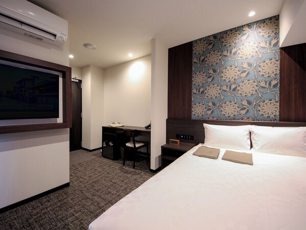 A hotel room with a bed, a desk, and a chair. There is a clock on the nightstand and an air conditioning unit on the wall. - Hotel and Spa Gift TAKAYAMA (Takayama)