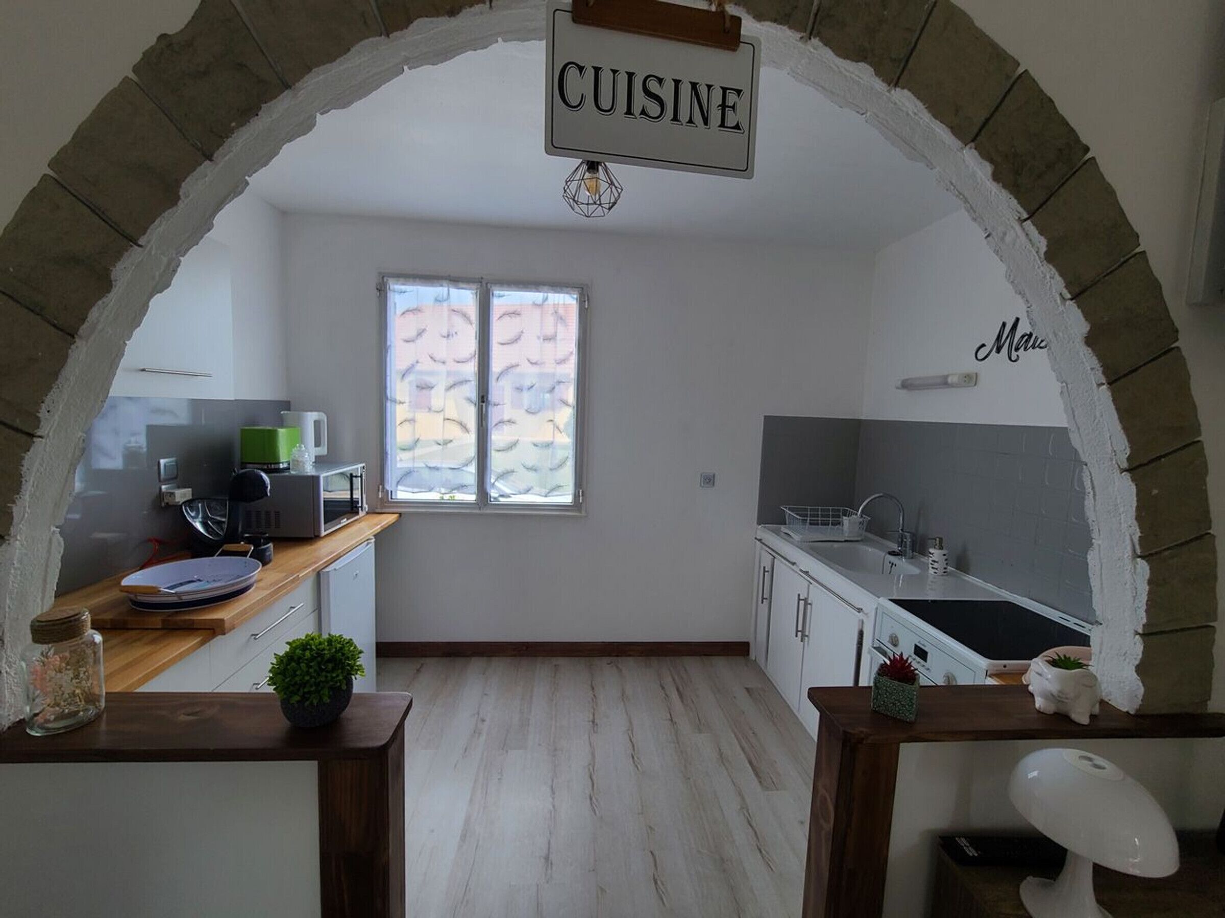Una cocina con un cartel que dice 'CUISINE', una ventana con vistas y una encimera con electrodomésticos.