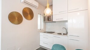Een moderne keuken met witte kasten, een ingebouwde magnetron en een spoelbak. Er zijn twee decoratieve wanddecoraties en een hanglamp.