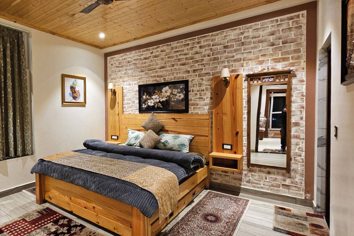 Ein Schlafzimmer mit einem hölzernen Bett, einer Backsteinwand, einer Holzbalkendecke und einem Fenster mit Vorhängen.