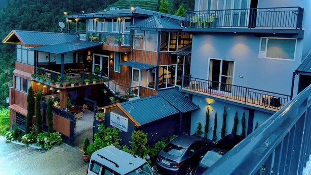 Un edificio de varios pisos con balcones, un cartel que dice 'Countryside Villa' y coches estacionados frente.