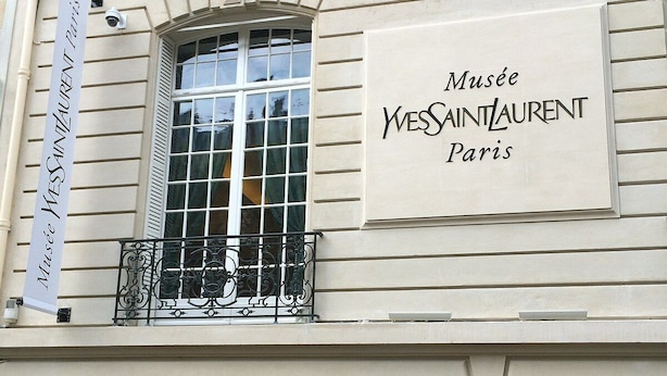 A building with a sign reading "Musée Yves Saint Laurent Paris" and a banner for "Maison Yves Saint Laurent".