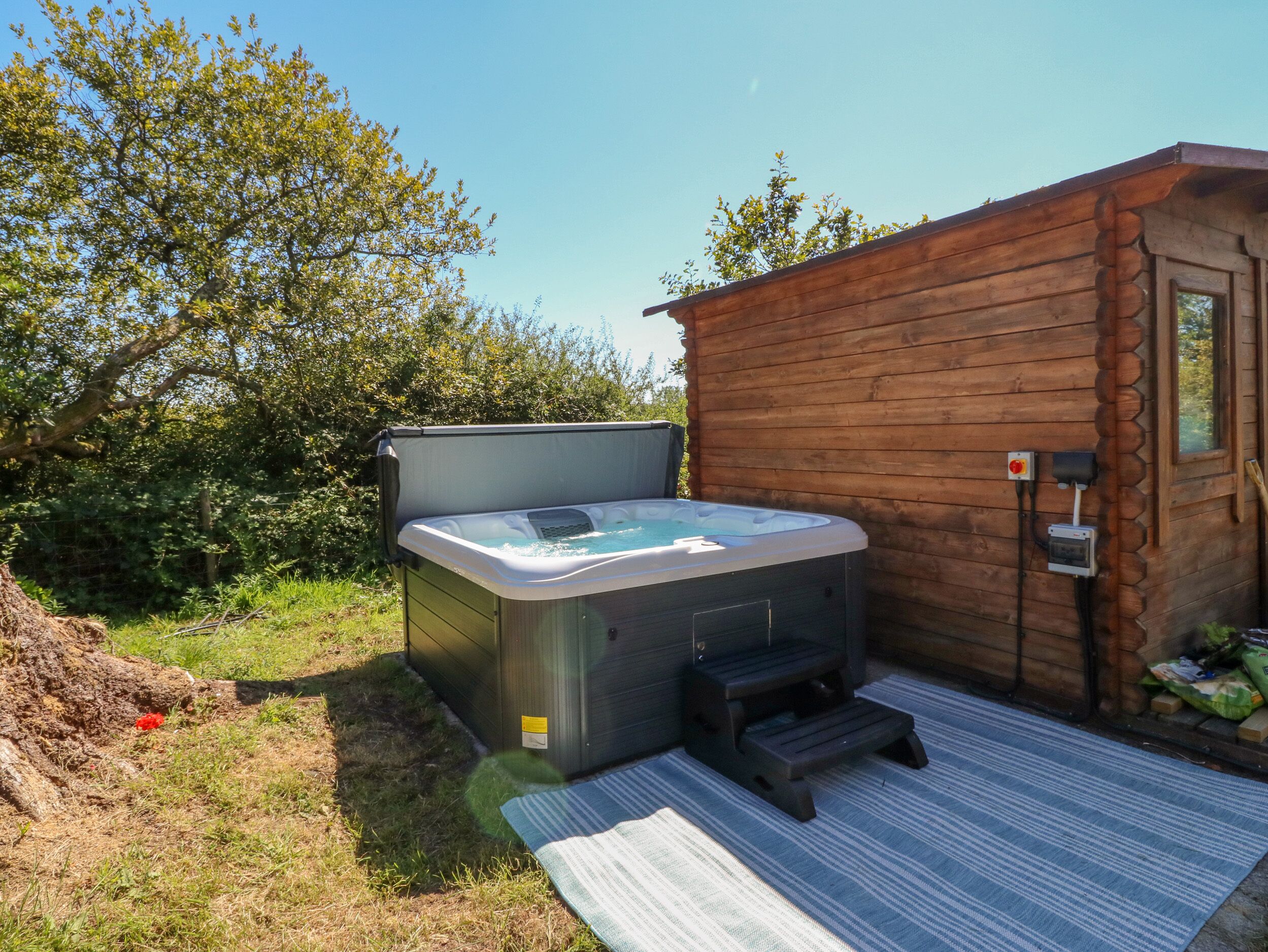 A wooden cabin with a hot tub and a small wooden deck.
