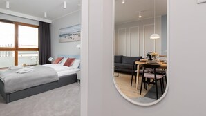 A modern bedroom with a bed, bedside table, and a large window. - Modern Apartment close to the Beach | Parking and Gym (Gdansk)