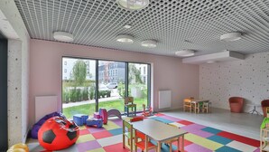 A brightly colored playroom with a large window, a table, chairs, bean bags, and a colorful floor. - Modern Apartment close to the Beach | Parking and Gym (Gdansk)