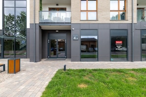 Un bâtiment moderne doté d’une entrée en verre, d’un balcon et d’une enseigne indiquant un commerce local.