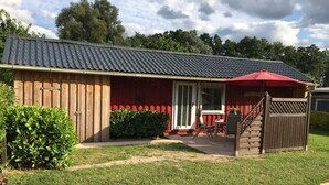 Un bâtiment en bois avec un toit rouge et une terrasse couverte.