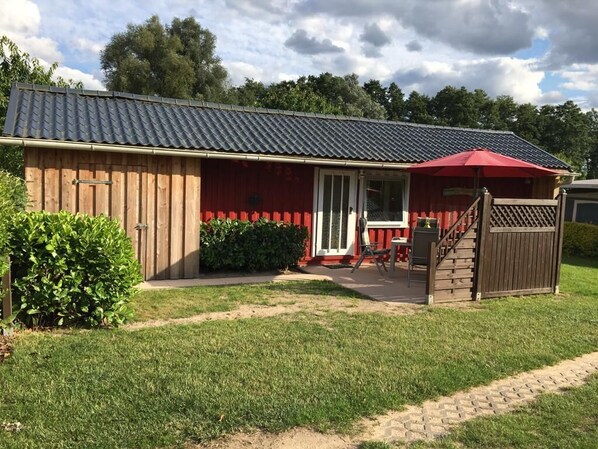 A wooden building with a red roof and a covered patio area.