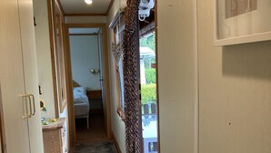 Un couloir étroit doté d’un sol recouvert de moquette, de meubles en bois et d’une porte donnant sur un balcon.