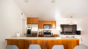Een moderne keuken met een centraal eiland, roestvrijstalen apparatuur en een flatscreen televisie.