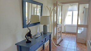 A hallway with a blue console table, a decorative sculpture, a lamp, and a mirror.