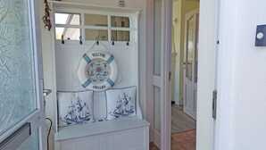 A door with a nautical-themed welcome sign, a coat rack, and two decorative pillows with ship designs.