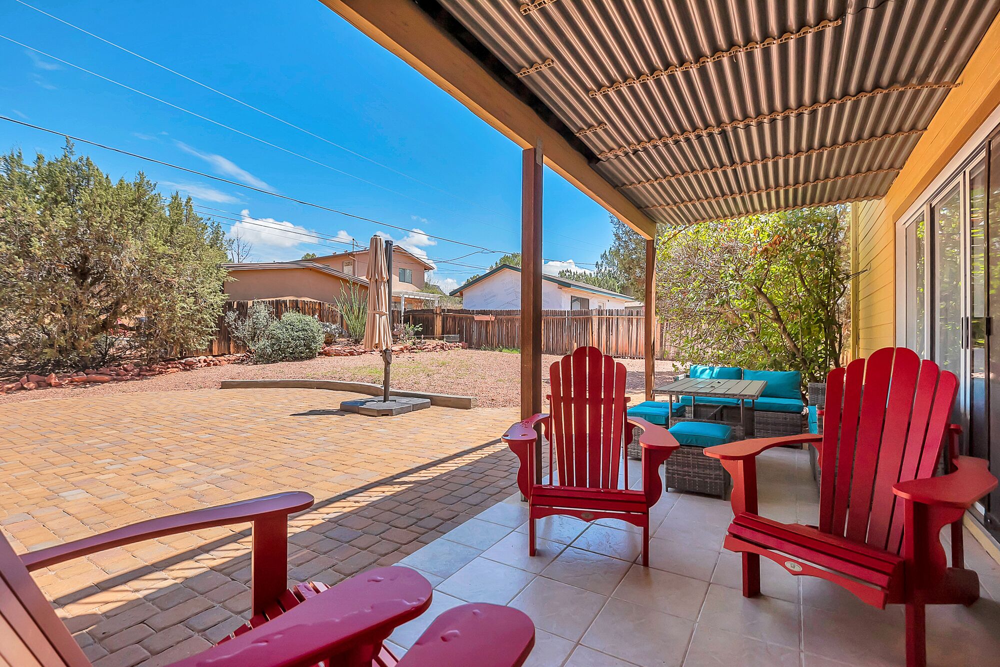 A covered patio area with red Adirondack chairs and a blue sofa.