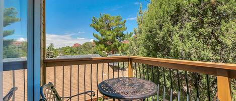 A balcony with a wooden railing, a metal table, and two metal chairs.
