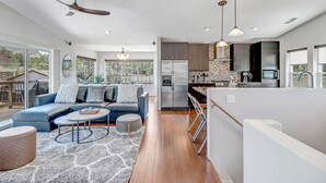 Una cocina moderna con refrigerador integrado, microondas y estufa. Hay un comedor con mesa y sillas, y un amplio ventanal con vistas al exterior.