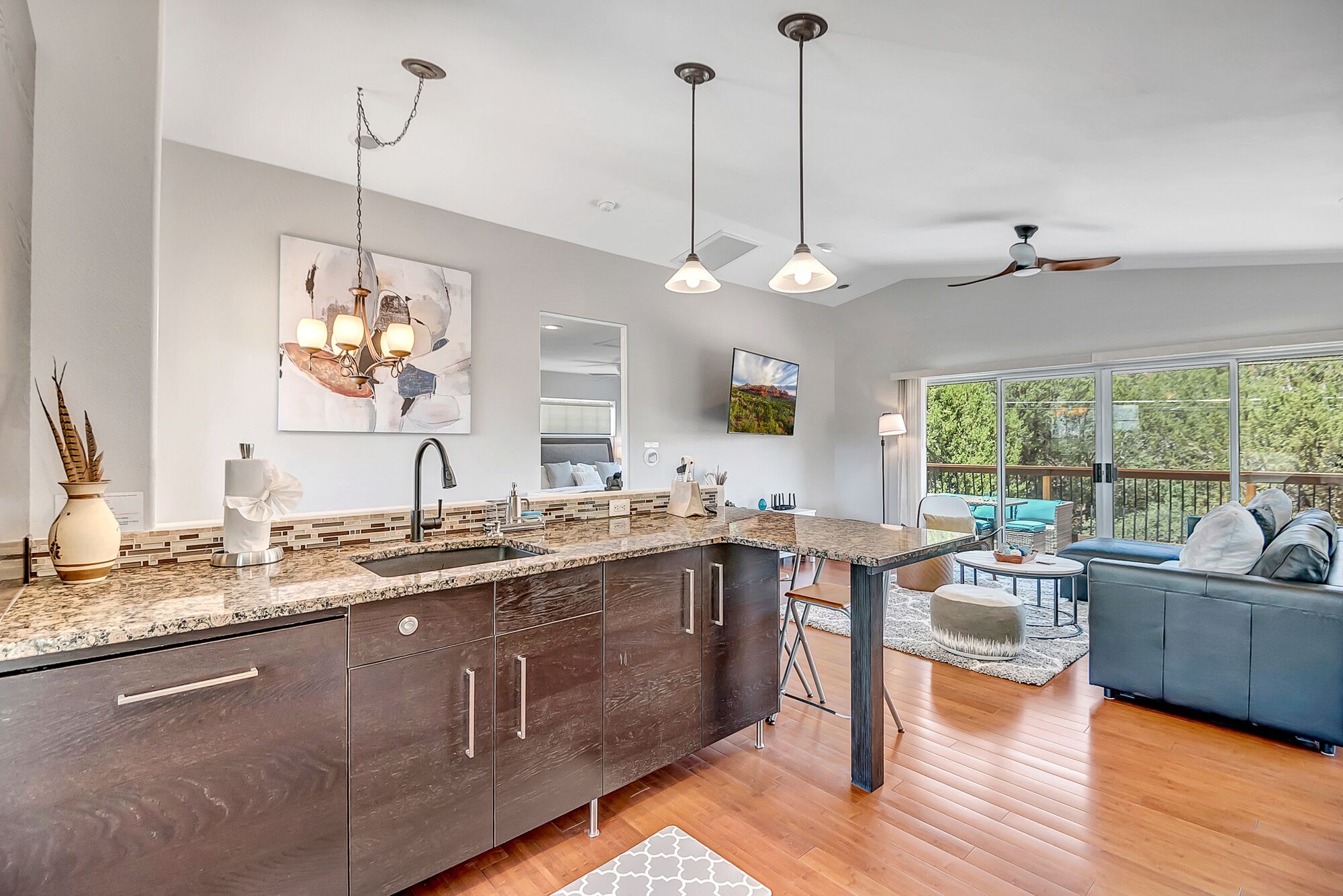 A modern kitchen with dark wood cabinets, a large island, and pendant lighting.