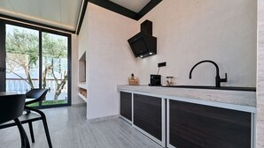 Una cocina moderna con estufa integrada, un ventanal amplio y un televisor negro montado en la pared.