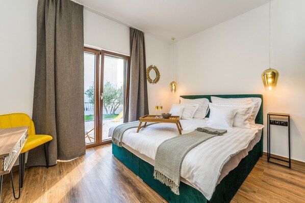 Un dormitorio con cama, mesita de noche, una silla y vistas al exterior.