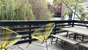 En træterrasse med to gule metalstole og et picnicbord.