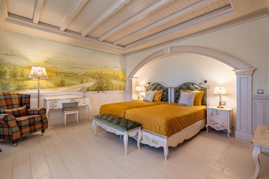 Un dormitorio con una cama grande, dos mesitas de noche, un escritorio, una silla y un mural en la pared.