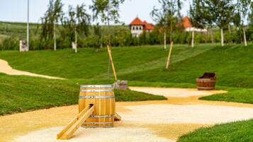 A wooden barrel with a lever on a gravel path in a park with grass and trees.