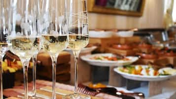 Un espace repas avec de nombreux verres à vin disposés sur une table en bois, entourée de différents plats et d’un buffet.