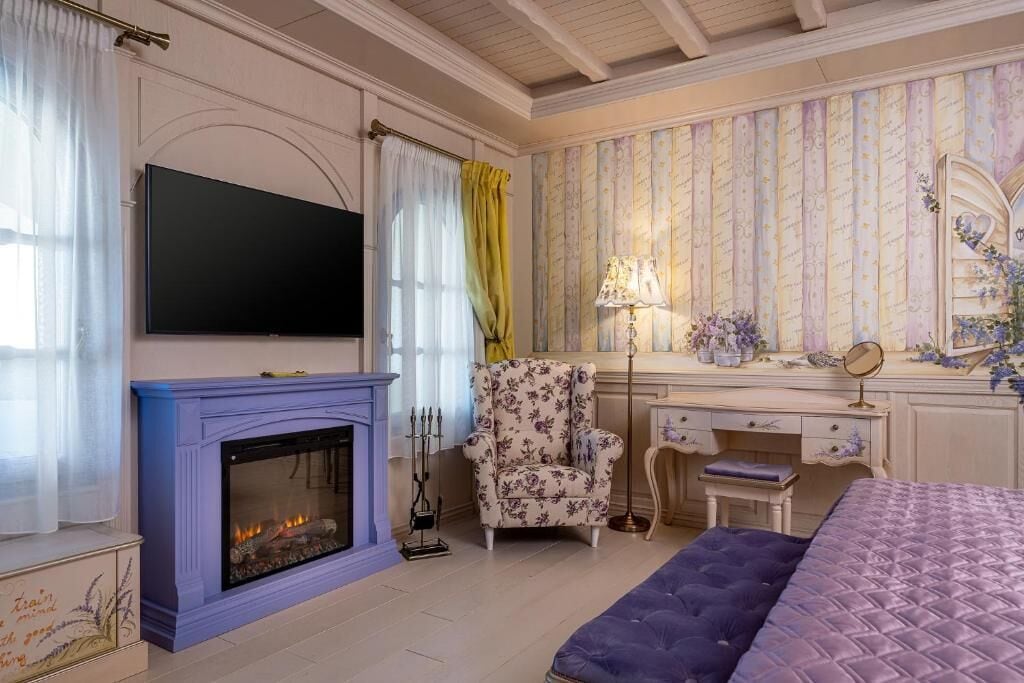 Une chambre avec une cheminée, une télévision, un bureau avec un miroir et un lit.