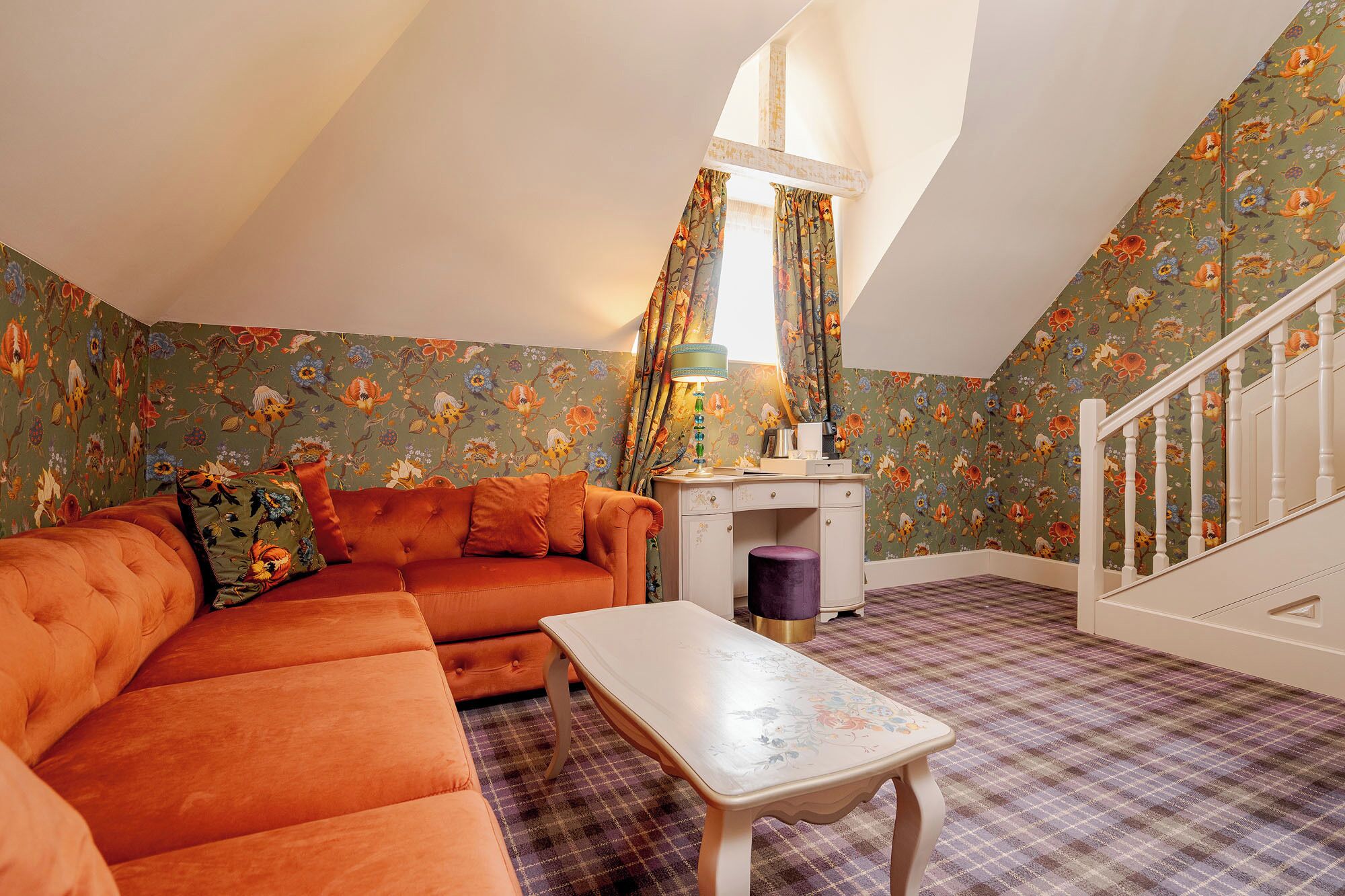 Une chambre mansardée chaleureuse, avec un canapé, une petite table et un bureau.
