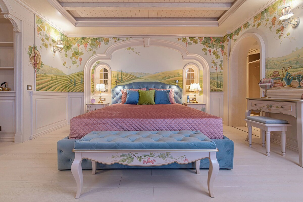 A bedroom with a large bed, a dresser, and a desk.