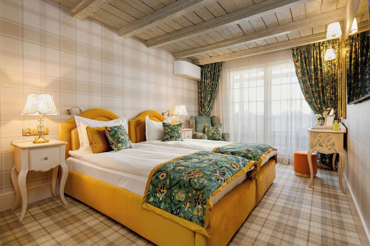 A hotel room with a large bed, a nightstand, a chair, a desk, and a mirror.