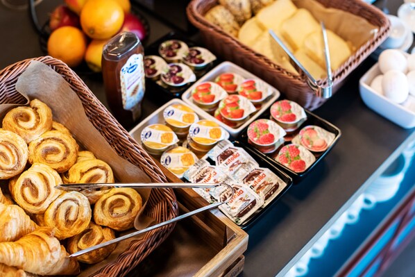 A buffet with various food items including pastries, fruits, and condiments. - B&B HOTEL Nyon (Nyon)