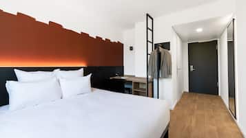 Una habitación de hotel con una cama grande, un escritorio y un armario.