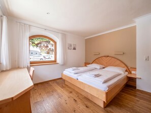 Un dormitorio con una cama de madera, un escritorio y una ventana con cortinas.