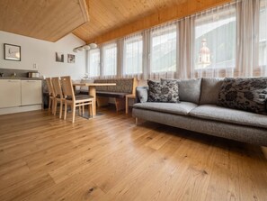 A cozy living area with a sofa, a dining table, and chairs. There is a kitchen area with cabinets and a countertop.